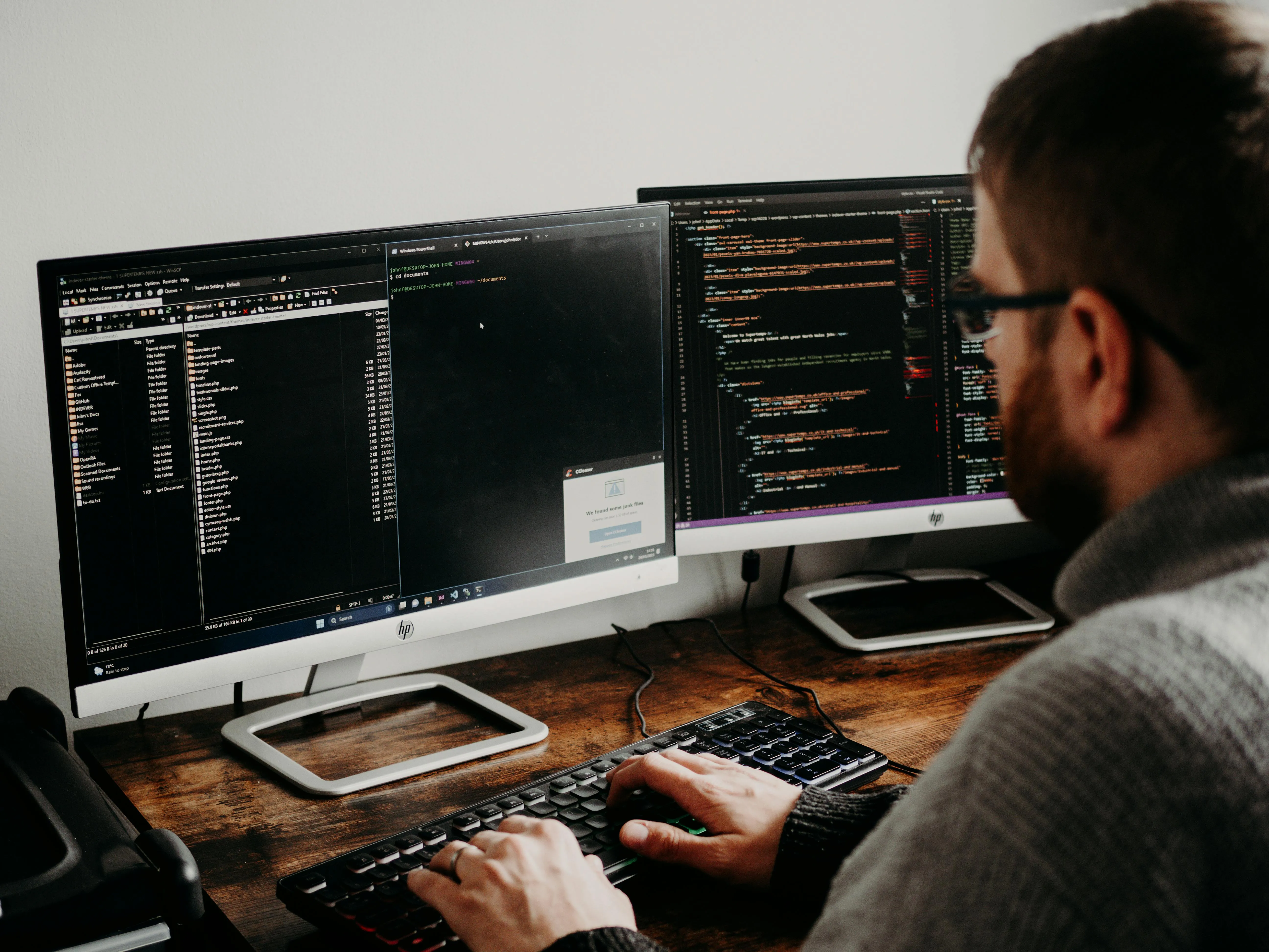 Developer working at a desk with two monitors displaying code