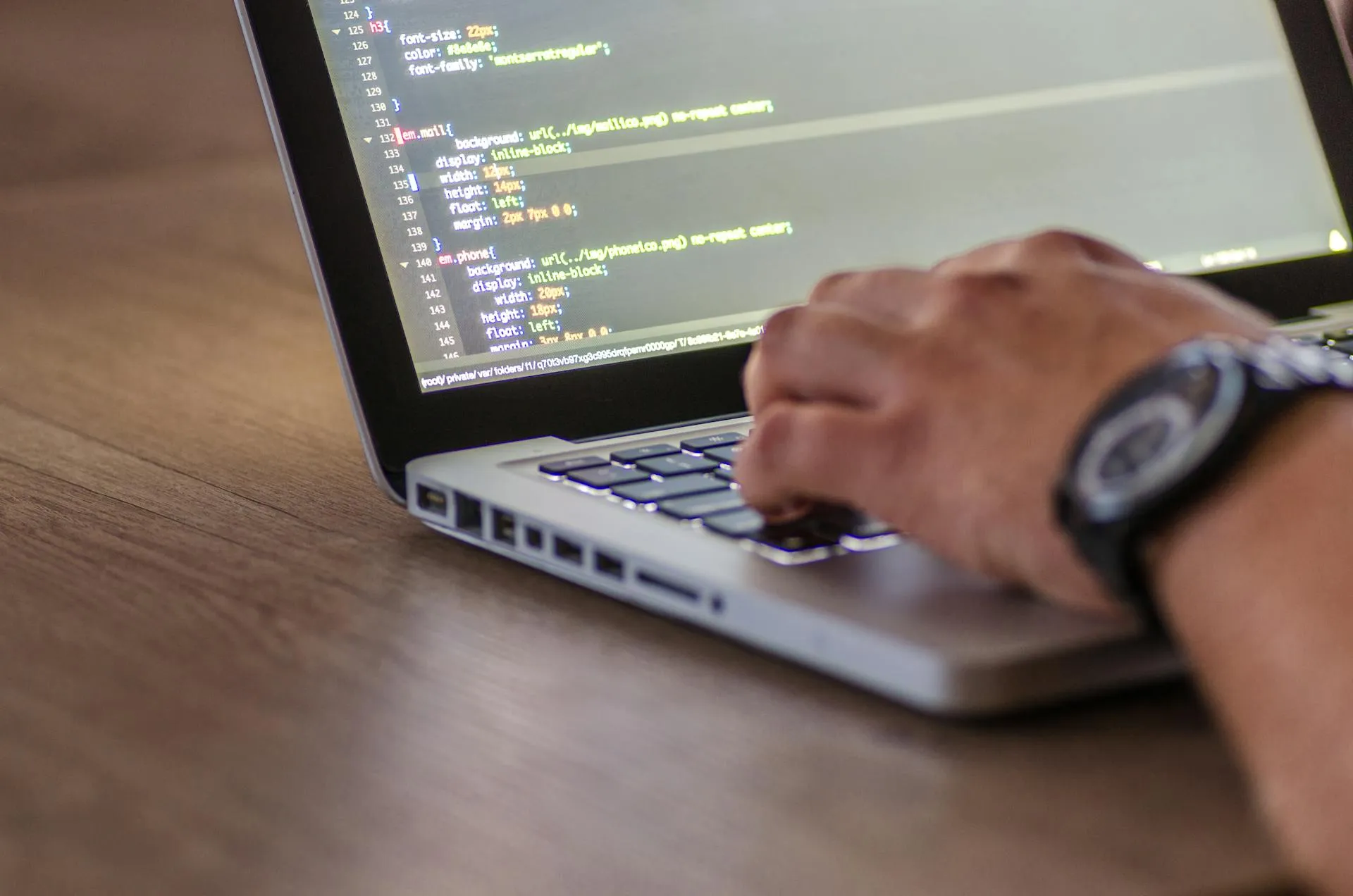 Close-up of someone typing code on a laptop